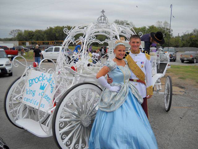 A couple of people in costume standing next to a carriage.