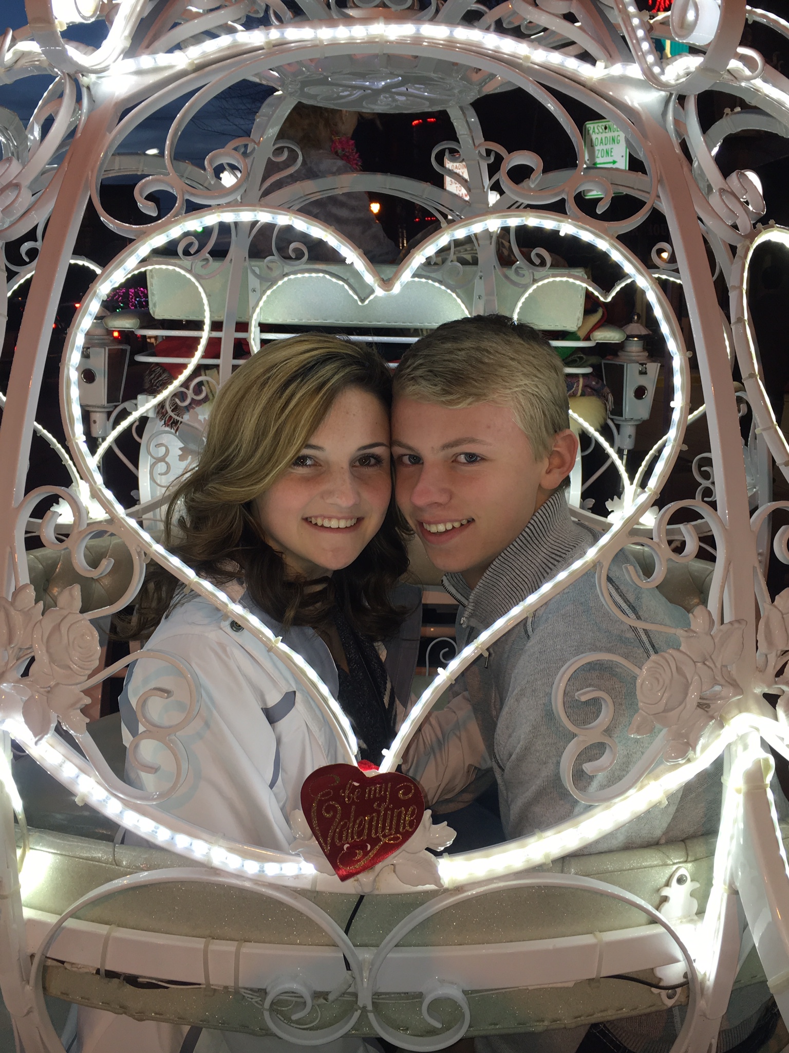 A man and woman are standing in front of a heart shaped frame.