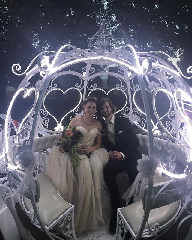 A couple is sitting in a carriage with lights around it.