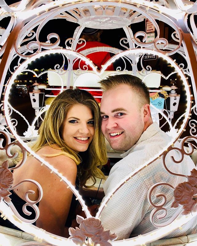 A man and woman posing for a picture in front of a heart shaped frame.