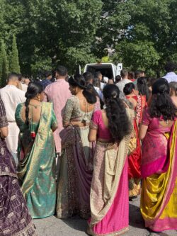 People in colorful sarees at outdoor gathering.